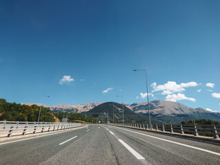 Fototapeta premium Driving highway mountain road in Greece on a sunny summer day with scenic cloudscape view