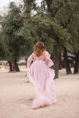 Fototapeta na wymiar young woman in a beautiful fluffy dress walks on the sand, from the back
