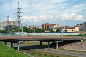 Massive car overpass in summer near the hills with houses. - obrazy, fototapety, plakaty