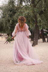 young woman in a beautiful fluffy dress walks on the sand, from the back
