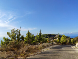 Driving mountain road near Kalamitsi village with clear blue sky, Lefkada island, Ionian sea coast, Greece. Sunny summer scenic day trip with long shadows