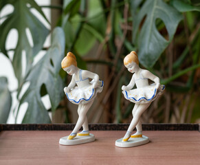 Vintage porcelain balerina girl figurines - on a wooden table with plants in the background © Menta