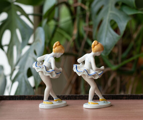 Vintage porcelain balerina girl figurines - on a wooden table with plants in the background © Menta