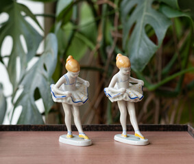 Vintage porcelain balerina girl figurines - on a wooden table with plants in the background © Menta