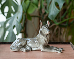 Mid-century modern porcelain figurine dog - on a wooden table with plants in the background