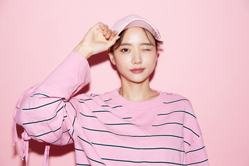 帽子をかぶったカジュアルな若い女性のピンク背景のポートレート