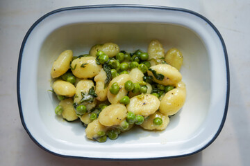 Homemade gnocchi with creamy sauce, green peas and spinach