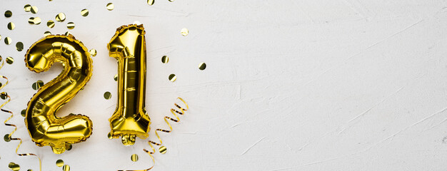 golden foil balloon number twenty one. Birthday or anniversary card with the inscription 21. gray concrete background.