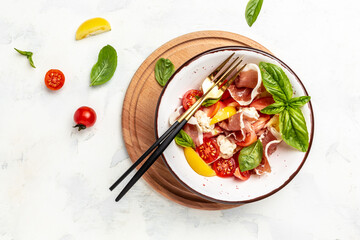 Salad with Prosciutto, ham jamon, tomatoes, cheese. Cold snacks. Food recipe background. Close up top view