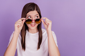 Photo of funny girl touch sunglasses look empty space isolated on violet background