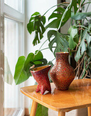 Mid-century modern ceramics - red crackled glaze vases - on a wooden table with plants in the...