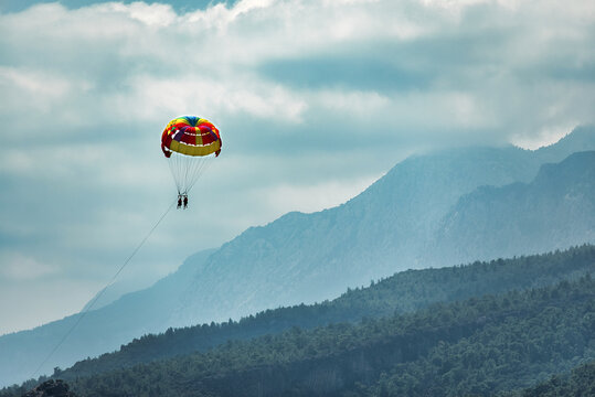 silhouette of happy couple parasailing on tropical sea. Summer extreme actions