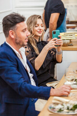 Attractive woman taking a photo during dinner party with friends
