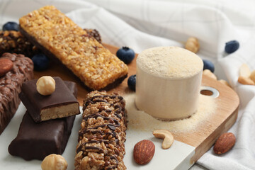 Fototapeta na wymiar Different energy bars, nuts, blueberries and protein powder on table, closeup