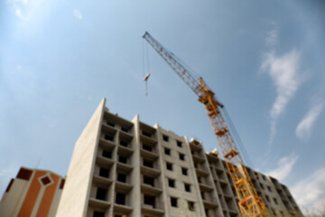 Fototapeta na wymiar Blurred view of unfinished building and construction crane outdoors