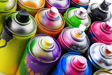 Used cans of spray paints as background, closeup. Graffiti supplies