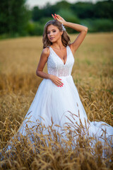 Fototapeta na wymiar beautiful young bride in a wheat field at sunset 