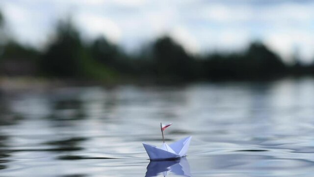 Kleines Papierschiff mit Flagge in den Wellen auf dem See