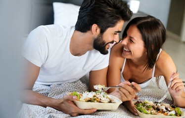 Healthy breakfast in bed. Young beautiful couple in love is sitting on bed and having breakfast.