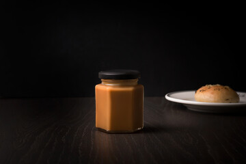 Salted homemade caramel in a jar. Dark background.