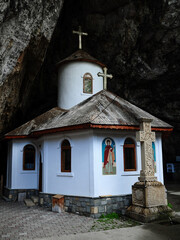 Small Chapel built at the entrance of a cave. A large stone Cross was carved at the entrance. Ialomita Gorges, Romania. Carpathia.