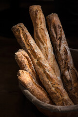 Freshly baked sourdough bread. Baguettes in a basket on a dark background.