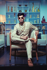 young Indian man sitting wearing traditional cloth and jewelry chain bracelet. show peaces in background