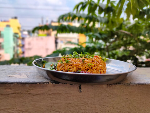 Stock photo of delicious popular South Indian rice dish puliyogare, its also called pulihora or puliyodarai garnished with dry chilli fresh coriander and curry leaves. one dish meal.