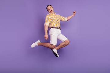 Portrait of funky positive carefree guy jump enjoy lifestyle on purple background