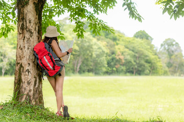 Women hiker or traveler with backpack adventure holding map to find directions and relax in the jungle forest outdoor for destination leisure education nature on vacation