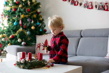 Little cute blonde toddler boy, making advent wreath at home