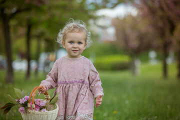 Beautiful toddler blond child, cute little girl in vintage rose dress, playing in the park springtime