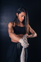 Athletic boxer female wraps bandages on her hands puts gloves for fight in gym. Workout, fitness concept.