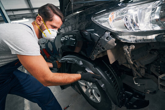 Man Pulling Out Car Wheel Arch Cover