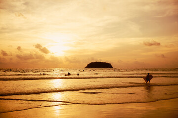 Sun over mountain silhouette paradise island.Surfboard on tropical beach in summer beach sunset.