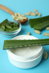 Concept of herb pills and cosmetics with aloe on blue background