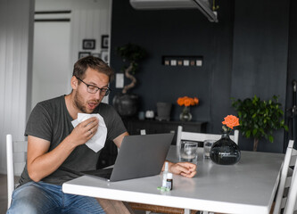 attractive nerdy man with glasses freelance working from home during the covid pandemic or flu