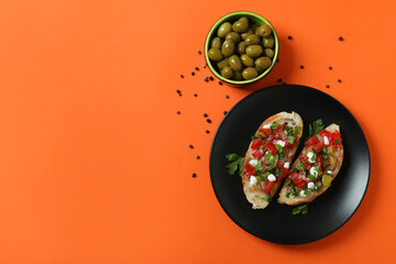 Delicious italian snacks bruschetta and ingredients on orange background