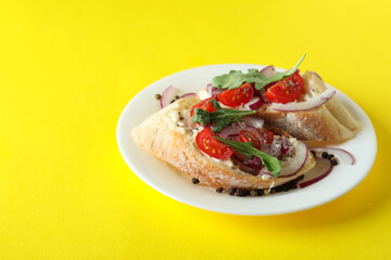 Plate with bruschetta snacks on yellow background