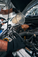 Worker turning over plastic cup while adding oil to engine