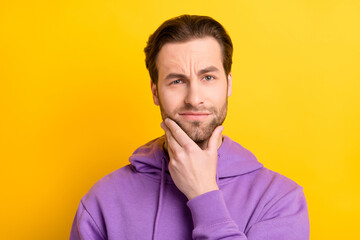 Photo of serious clever guy hand chin think look camera wear violet hoodie isolated yellow color background