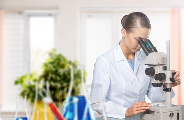 Young female scientist looking through a microscope.