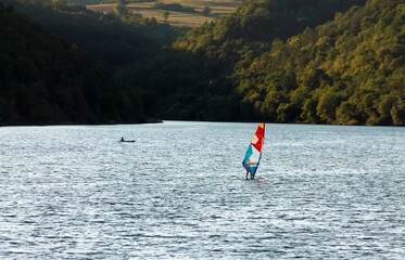 Windsurfer surfing on the lake at sunset, kayak in the background . Adobe RGB color space