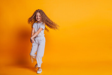 beautiful girl spinning in white t-shirt on yellow background in studio 