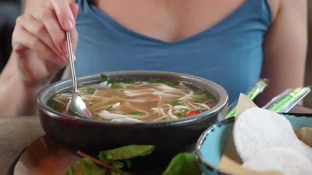 close-up of a plate, someone eating pho bo soup.