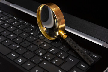 Magnifying glass on mobile laptop keybord, searching information, enlarge knowledge or inspect online and offline facts