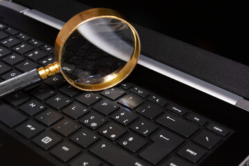 Magnifying glass on mobile laptop keybord, searching information, enlarge knowledge or inspect online and offline facts