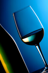 Italian white wine glass of wine pecorino verdicchio Marche stylized glass in backlight whit bottle  on blue background