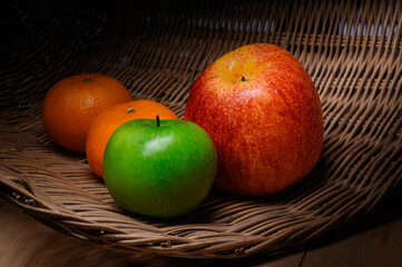 Fresh apples and oranges in wicker basket.