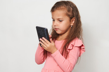 Fototapeta premium Portrait of a little girl using cell phone against white background